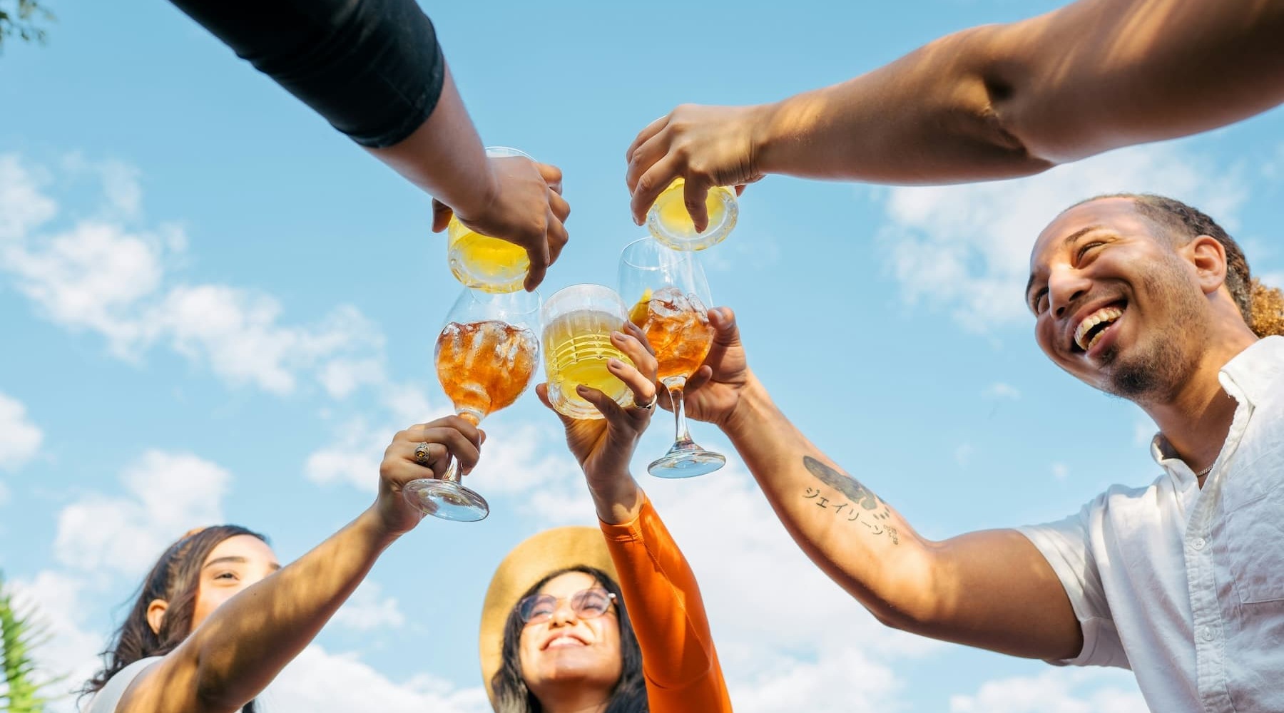 a group putting drinks together in celebration outdoors